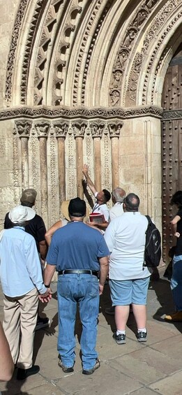 A group of people standing in front of a large, intricately carved stone doorway. 3