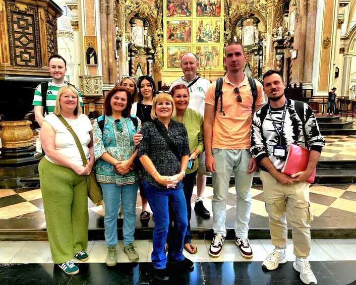 A group of people standing in a church with ornate architecture and religious paintings. 4