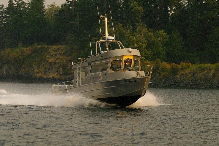 A boat named 'SEEKER' moving through a body of water with a forested shoreline in the background. 2