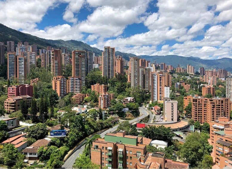 A densely populated urban area with high-rise buildings, a winding road, and mountains in the background. 1