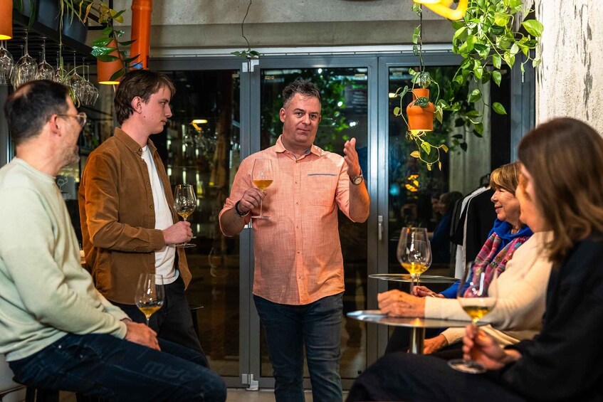 A group of people at an indoor social gathering, some holding wine glasses. 2