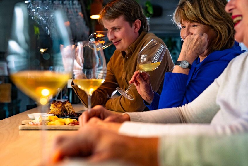 People sitting at a table with wine glasses and food. 4