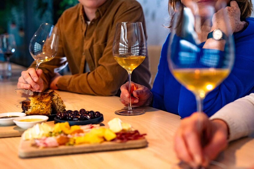 Two people sitting at a table with wine glasses and a charcuterie board. 3