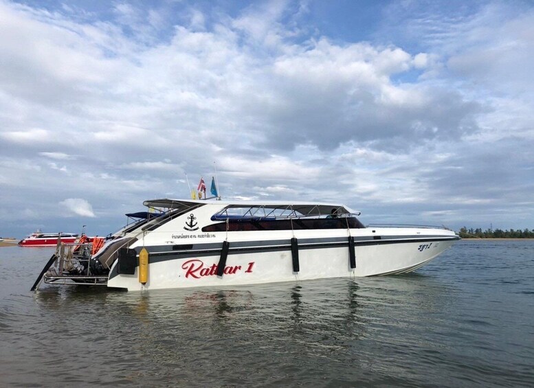 A white speedboat named 'Katar 1' with a cabin and a flag on top, docked in calm waters. 4