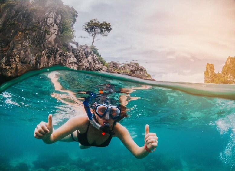 A person snorkeling underwater with a rocky landscape above. 2