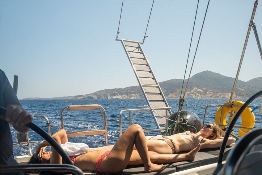 A sailboat with two people lying on deck, a lifebuoy, and a ladder. 3