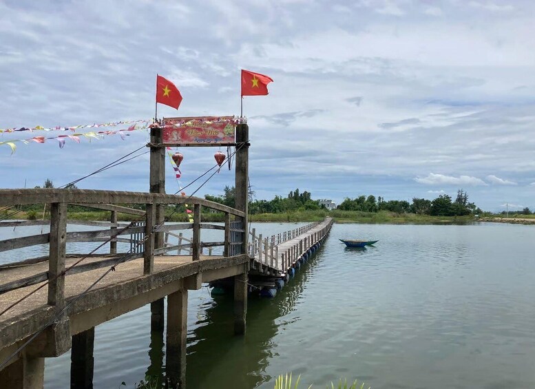 A wooden bridge over water with flags and a boat. 4