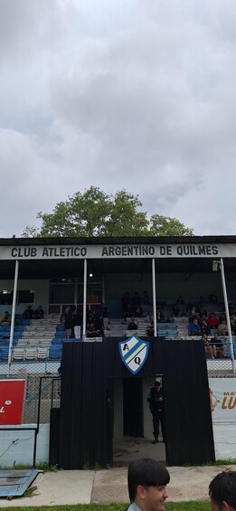 A sports stadium with a sign reading 'CLUB ATLETICO ARGENTINO DE QUILMES' and a logo above the entrance. 5
