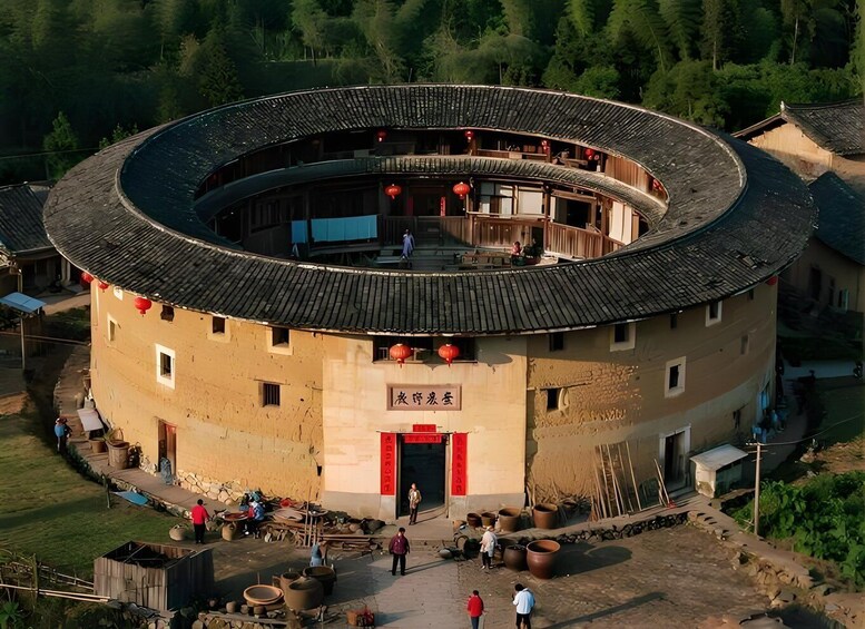 A traditional round building with a tiled roof, surrounded by greenery and people. 4