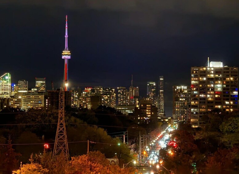 A nighttime cityscape with a prominent tower lit up in the center, surrounded by illuminated buildings and a busy street. 3