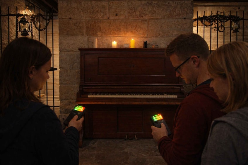 A piano in a stone-walled room with two lit candles on top. 1