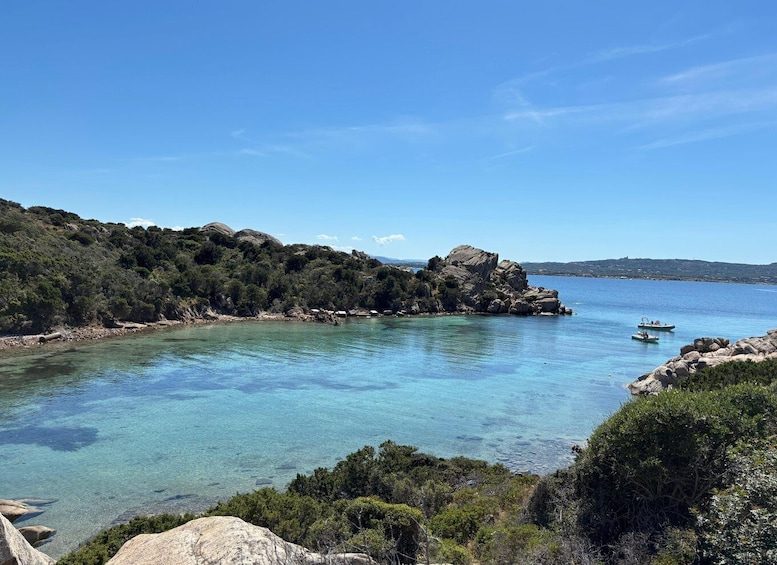 A coastal landscape with clear turquoise waters, rocky outcrops, and dense greenery. 5