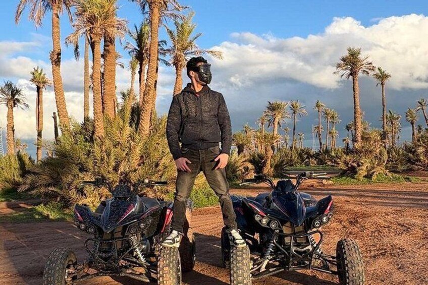A person standing between two all-terrain vehicles in a desert-like environment with palm trees. 2