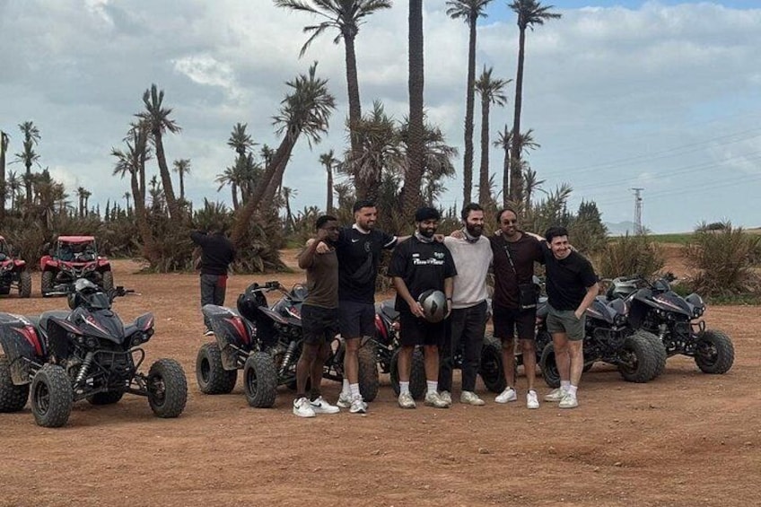 A group of people standing with ATVs in a desert landscape with palm trees. 5