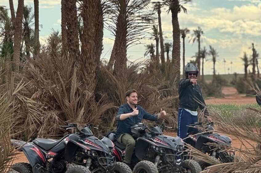 Two people on all-terrain vehicles in a desert with palm trees. 1