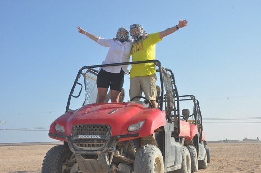 Due persone in piedi su un quad rosso Honda nel deserto. 5