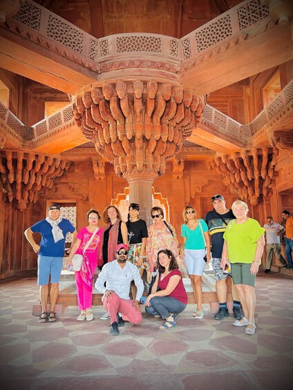 A group of people in a historic building with intricate wooden carvings and a large, ornate ceiling. 5