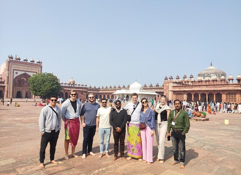 A group of people standing in front of a large, historic building with domes and arches. 4