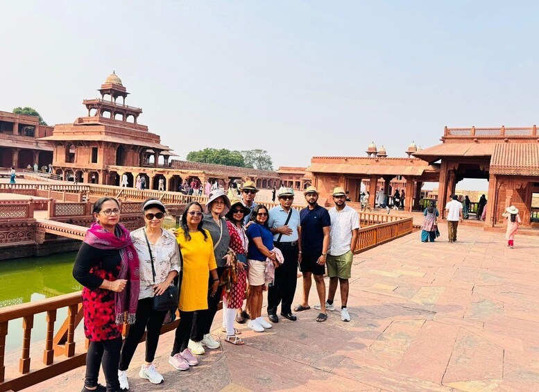 A group of people standing on a bridge with historical architecture in the background. 2