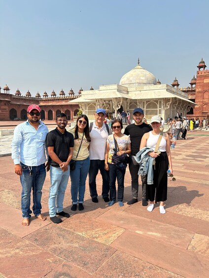 A group of people standing in front of a large historical building with domes and arches. 1