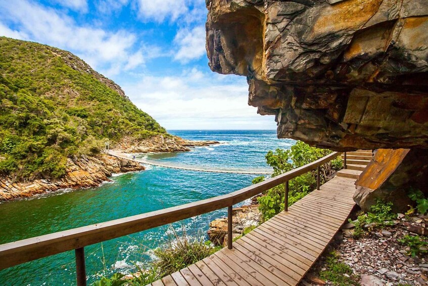 A coastal walkway with a view of turquoise waters and a rocky cliff. 3