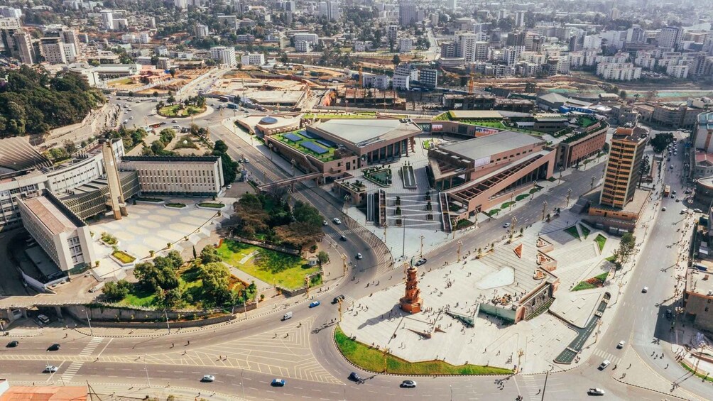 An urban area with a central roundabout, surrounding buildings, and a large open plaza. 4
