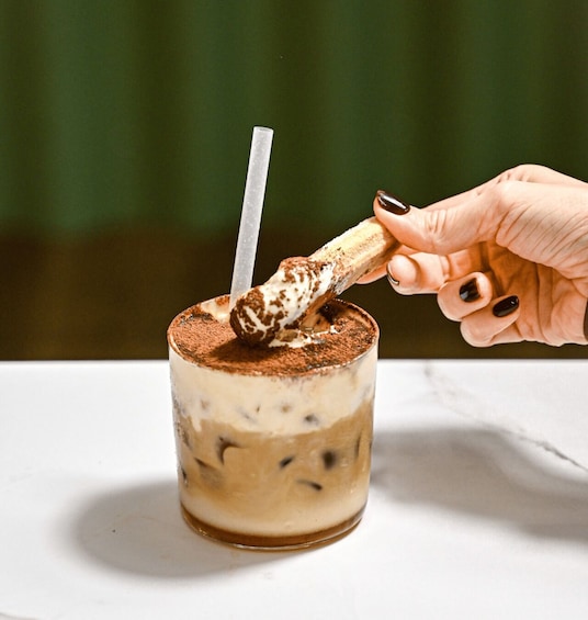 A hand stirring a layered beverage with a straw in a glass. 2