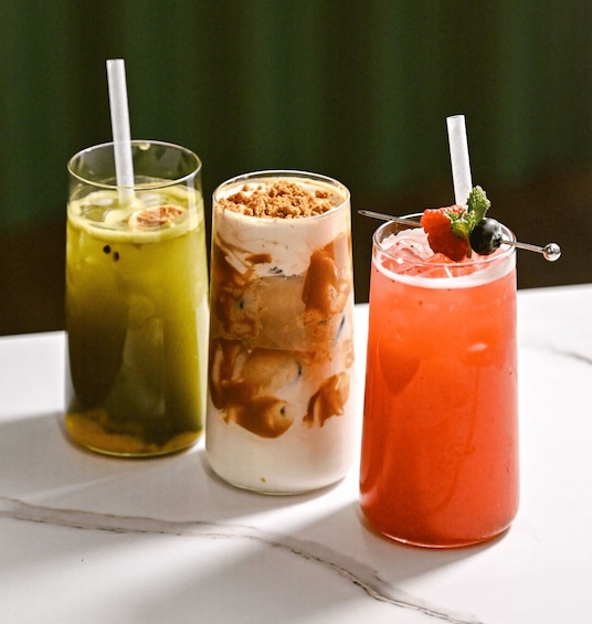 Three drinks in glasses with straws, one with a strawberry garnish. 5