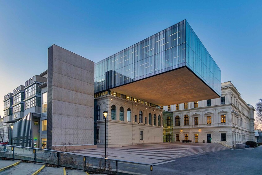 A modern building with a glass facade and a classical structure with arched windows. 5