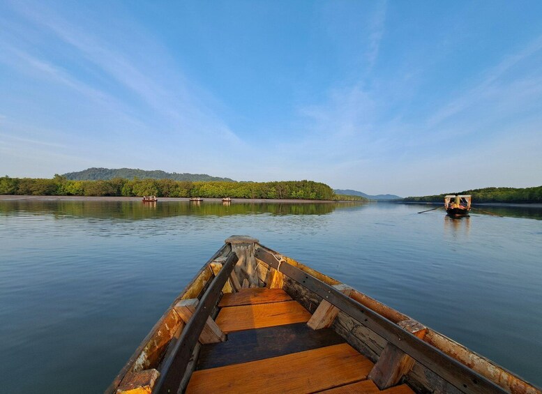 A wooden boat on calm water with a forested island in the background. 1