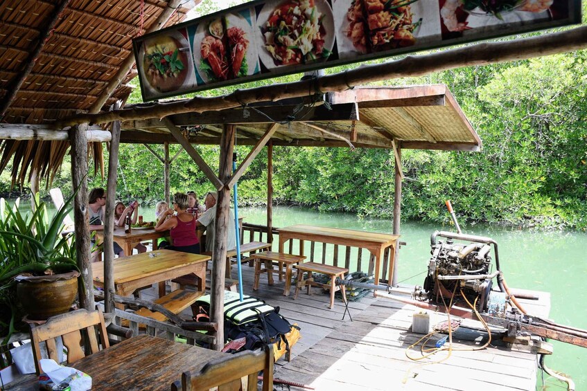 A wooden dock with tables and benches, surrounded by lush greenery and a calm body of water. 5