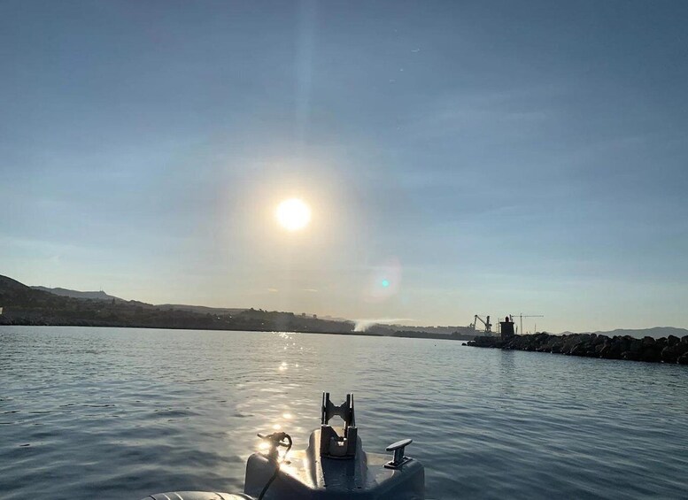 A boat on calm water with the sun low on the horizon, reflecting off the surface. 4