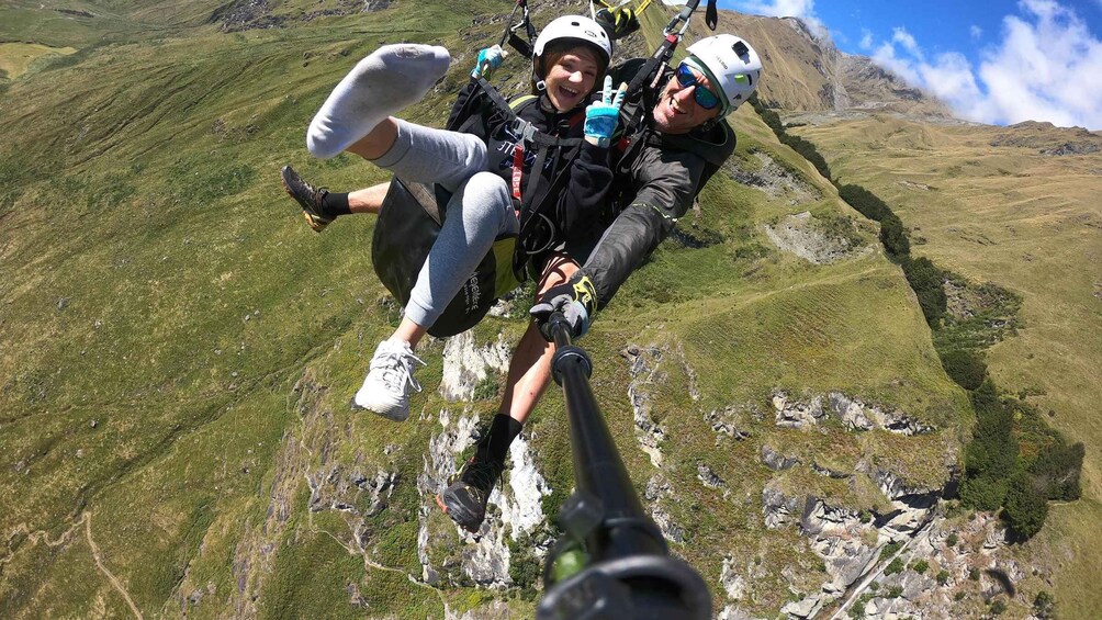 Two people skydiving with a mountainous landscape below. 2