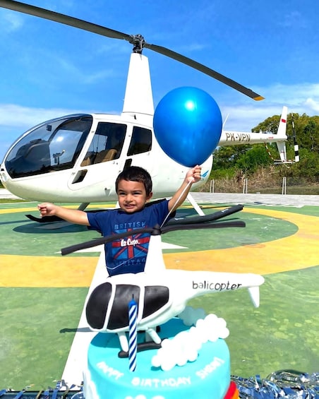 A child holding a blue balloon in front of a helicopter. 4