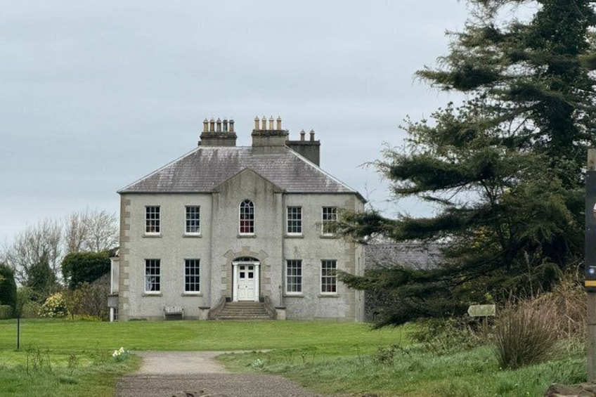 A large, two-story stone building with a symmetrical facade, a central entrance, and a well-maintained lawn in front. 4