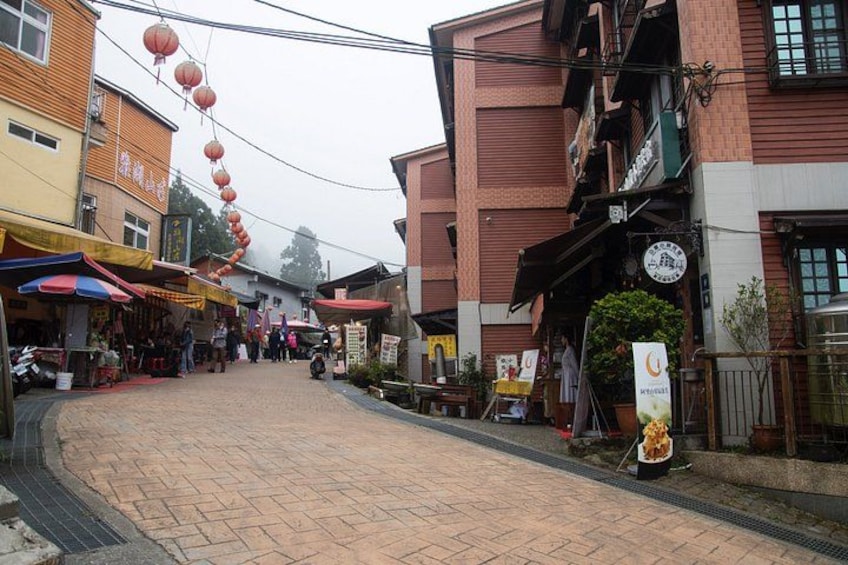 A street with shops, red lanterns, and a brick pavement. 4