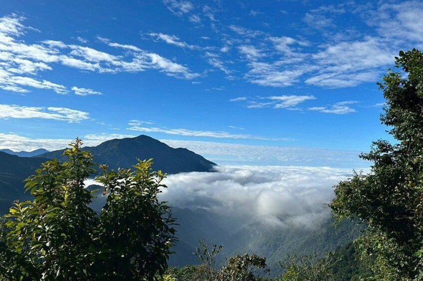 A mountain landscape with a clear sky, dense cloud cover, and lush greenery. 1