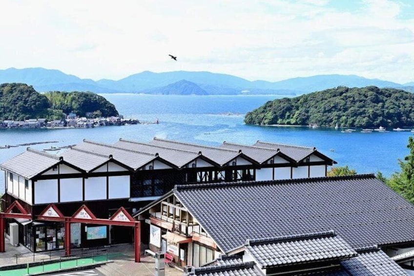 A traditional Japanese building with a tiled roof, overlooking a body of water with islands in the distance. 2