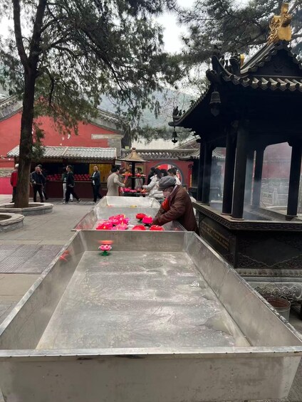 A traditional Chinese temple with a large incense burner and people performing rituals. 2