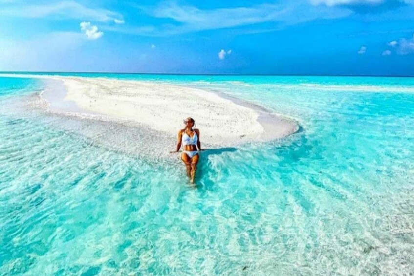 A person walking on a beach with clear turquoise water. 4