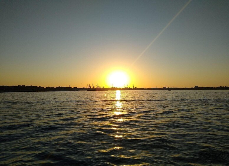 A sunset over a body of water with industrial structures silhouetted against the sky. 2