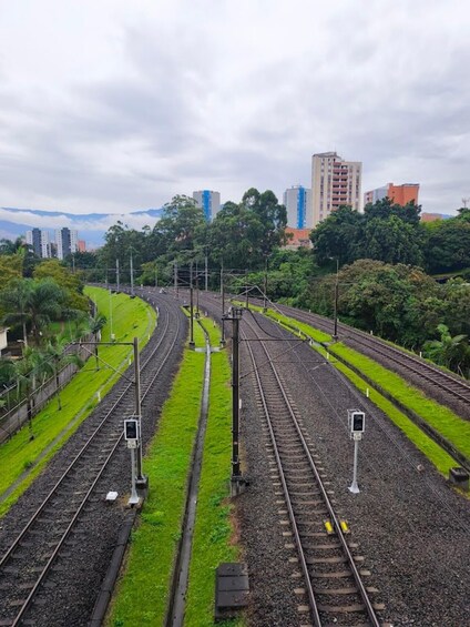 A railway junction with multiple tracks, surrounded by greenery and urban buildings in the background. 2