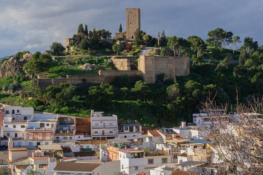 A town with buildings, a hilltop tower, and greenery. 4
