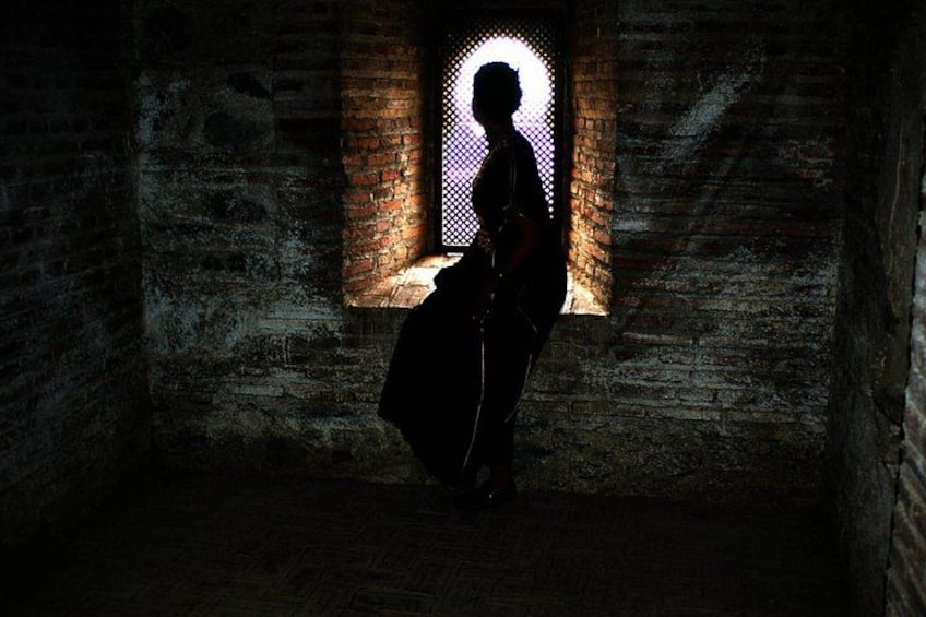 A person standing in a dimly lit room with a window casting a silhouette. 2