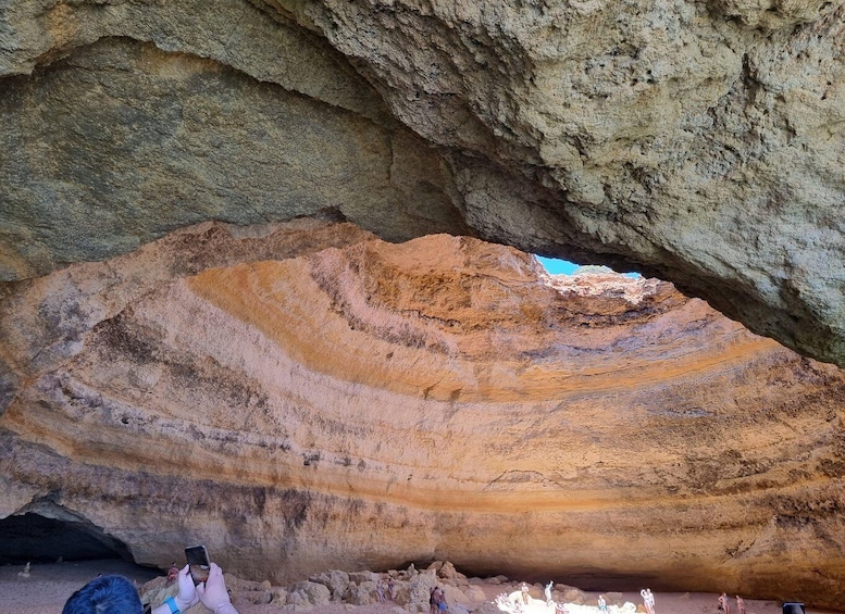A large rock formation with layered colors and a cave entrance. 5