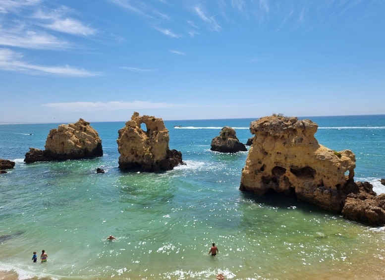 A clear blue sea with rocky formations and people swimming. 4