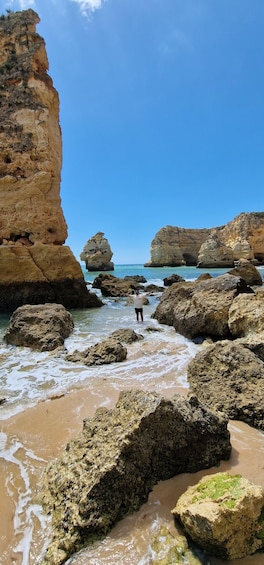 A rocky coastline with large boulders and cliffs under a clear sky. 1