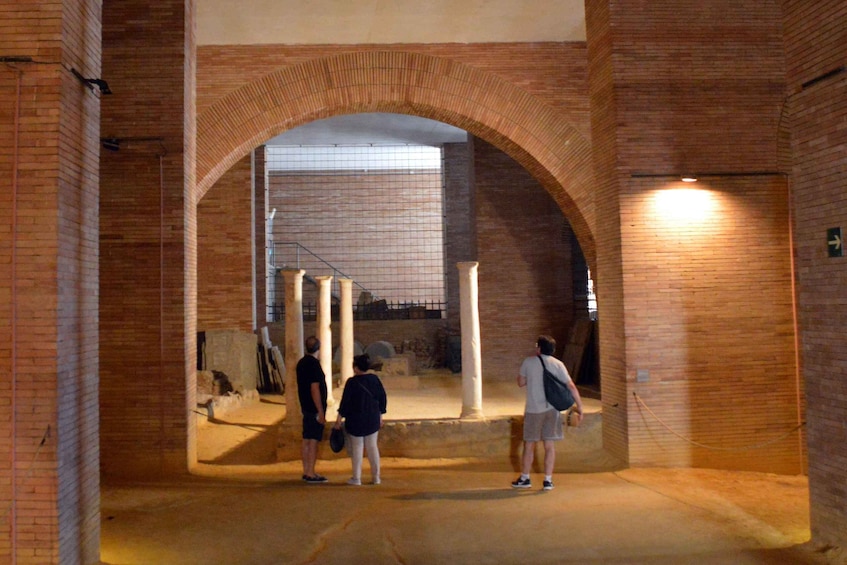 An arched brick structure with people standing inside. 4