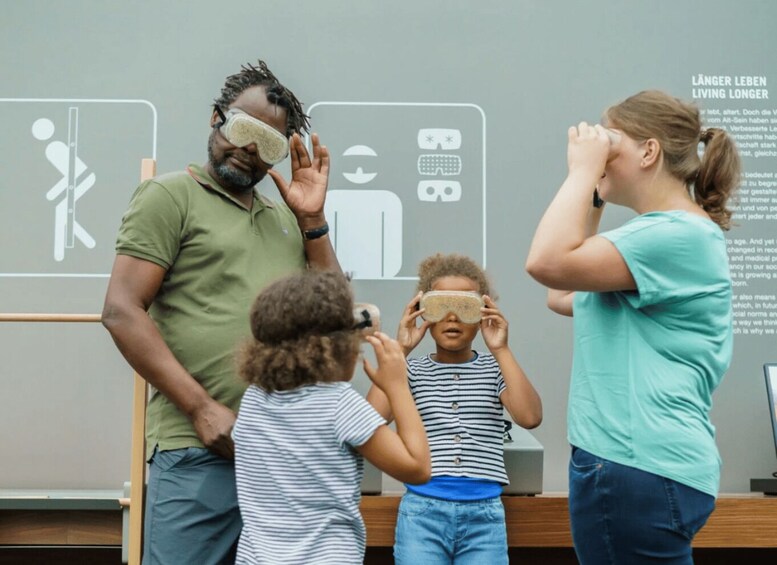 People wearing eye patches, standing in front of a sign with icons and text. 3