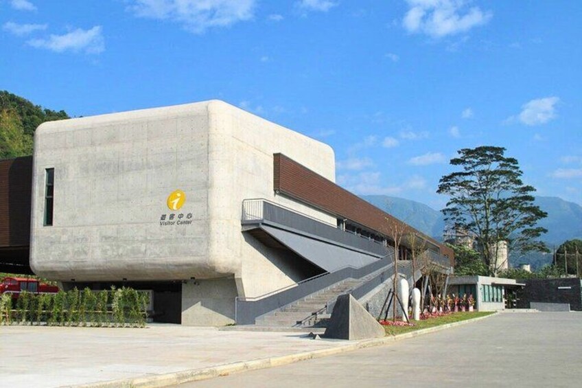 A modern building with a unique architectural design, a visitor center sign, and a staircase leading up to it. 4